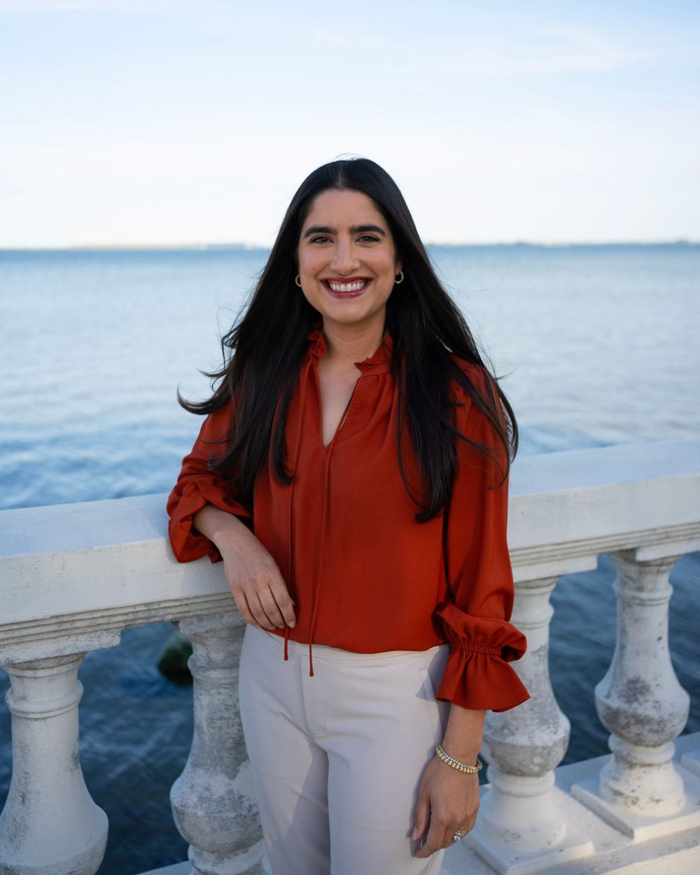 Dr. Rosie Muratides smiling at a white balustrade on the waterfront